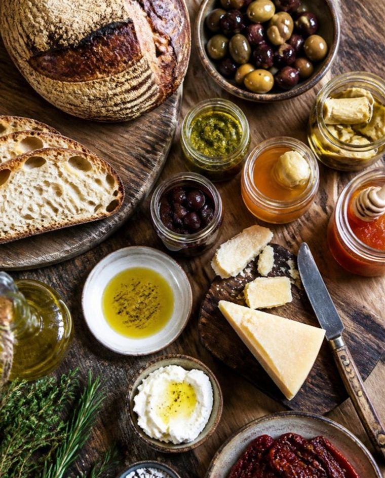 Artisan bread, olives, cheese and preserves on a wooden table
